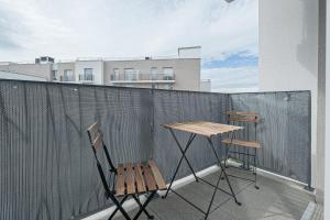 two chairs and a wooden table on a balcony at Coco - Appartement F4 à 10 minutes de Disneyland Paris in Bailly-Romainvilliers
