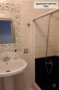 ein Bad mit einem Waschbecken und einer Dusche mit einem Spiegel in der Unterkunft Martil Center Apartments in Martil