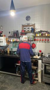 Un uomo in piedi in una cucina che prepara il cibo di Pousada Plantar e Cuidar a Santa Cruz do Escalvado