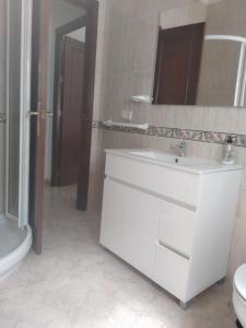 uma casa de banho com um lavatório, um WC e um espelho. em El 20 em Barbate