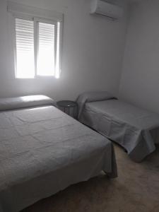 um quarto com 2 camas e uma janela em El 20 em Barbate