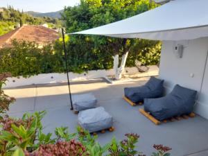 a patio with blue cushioned chairs and an umbrella at Modern Apartment 10mins from the Beach in Kefallonia