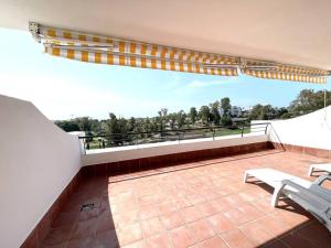 馬貝拉的住宿－Ático Dúplex en Guadalmina，阳台设有长凳,享有树林美景。