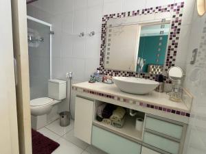uma casa de banho com um lavatório, um espelho e um WC. em Apart. centro Ribeirão Hospital São Lucas em Ribeirão Preto