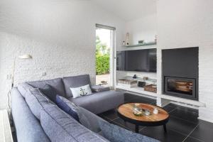 a living room with a blue couch and a fireplace at Bungalow near beach with large private garden - not for companies in Ouddorp
