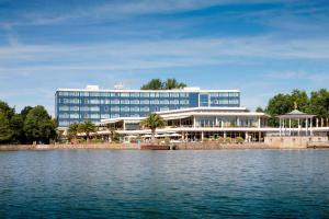 ein großes blaues Gebäude neben einem Wasserkörper in der Unterkunft Courtyard by Marriott Hannover Maschsee in Hannover