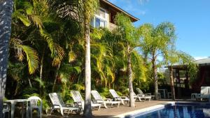 a group of chairs sitting next to a swimming pool at Pousada Morro do Rosa in Praia do Rosa
