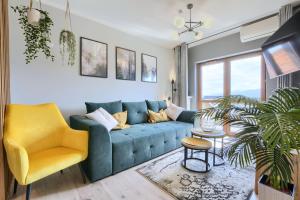 un salon avec un canapé bleu et un fauteuil jaune dans l'établissement Apartament AREKA A16 Green Resort - klimatyzacja, basen, sauny, jacuzzi, siłownia, à Szklarska Poręba