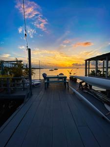 a wooden deck with a bench and a sunset on the water at Saigon Bay Bed & Breakfast in Bocas del Toro