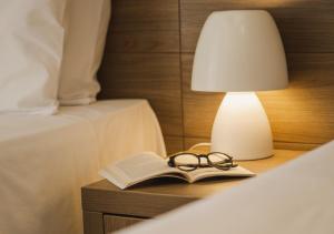 a book and glasses on a nightstand with a lamp at Hotel Ponta Verde Praia do Francês in Praia do Frances