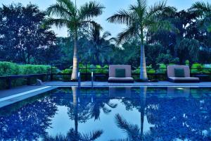 a swimming pool with two chairs and palm trees at JW Marriott Pune in Pune