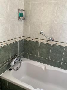 a white bath tub in a bathroom with green tiles at Hotel Mar Azul in Espinho