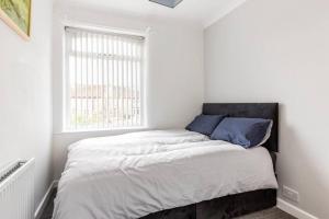 a bed in a white room with a window at Memory Lane - beautifully renovated house close to motorway networks in Shevington