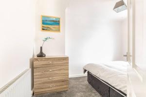 a bedroom with a dresser and a bed in it at Memory Lane - beautifully renovated house close to motorway networks in Shevington