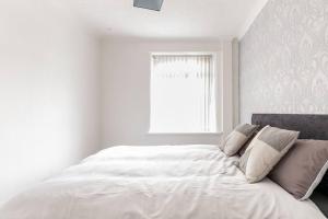 a bedroom with a large white bed with a window at Memory Lane - beautifully renovated house close to motorway networks in Shevington