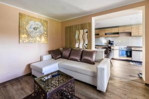 a living room with a white couch and a kitchen at Fekete Orchidea Apartman in Balatonkenese