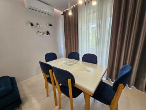 a dining room with a white table and blue chairs at Tower Bridge Apartment in Tirana