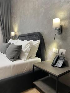 a bedroom with a bed with a phone and a table at Domus Hotel & Apartments in Shëngjin