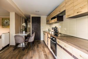 a kitchen with wooden cabinets and a table with chairs at Fekete Orchidea Apartman in Balatonkenese