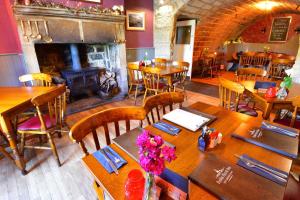 un restaurante con mesas y sillas de madera y chimenea en Robin Hood Inn, en Hebden Bridge