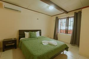 a bedroom with a green bed and a window at Quepos Inn in Quepos