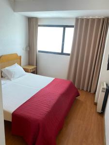 a bedroom with a large bed with a red blanket at Hotel Mar Azul in Espinho