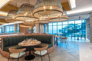 un restaurante con un sofá verde, mesas y ventanas en Sofitel Barú Cartagena, en Cartagena de Indias