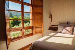 a bedroom with a bed and a large window at Casarão do Vale dos Vinhedos in Bento Gonçalves
