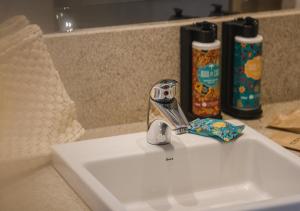 a bathroom sink with a faucet and two bottles of toothpaste at Hotel Ponta Verde Praia do Francês in Praia do Frances