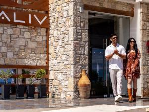 un hombre y una mujer caminando fuera de un edificio en Aliv stone suites & spa en Agios Nikolaos