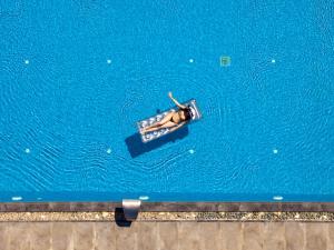 a person swimming in a pool of blue water at Aliv stone suites & spa in Agios Nikolaos