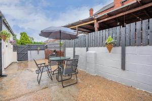 a table and chairs with an umbrella on a patio at *2a* ground floor house setup for your most amazing & relaxed stay + Free Parking + Free Fast WiFi in Beeston