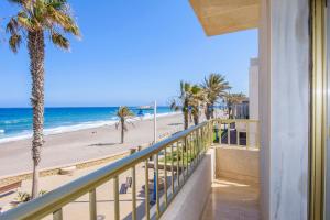 a balcony with a view of the beach and palm trees at Miramar in Carboneras