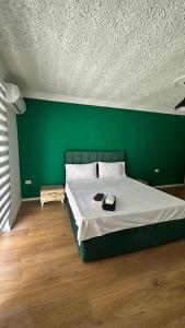 een groene slaapkamer met een bed met een groene muur bij Host Elios Tirana in Tirana