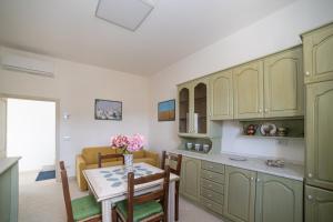 una cucina con armadi verdi e un tavolo con fiori di La Casa degli Dei a San Gimignano