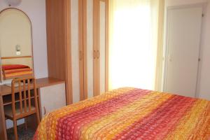 Schlafzimmer mit einem Bett, einem Schminktisch und einem Spiegel in der Unterkunft Hotel Apis in Rimini