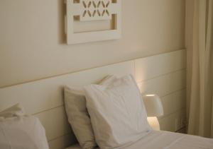 a bed with a white pillow and a picture on the wall at Hotel Ponta Verde Praia do Francês in Praia do Frances