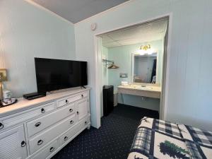 a bedroom with a dresser with a television and a bathroom at American Boutique Inn - Lakeview in Mackinaw City