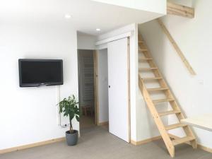 a living room with a tv and a staircase at Logement entier à la campagne proche du circuit et du zoo de la Flèche in Yvré-le-Pôlin +5 photos