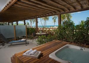 a hot tub sitting on a wooden deck with the ocean at Hotel Ponta Verde Praia do Francês in Praia do Frances