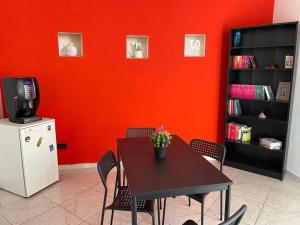 ein Esszimmer mit einem Tisch und einer roten Wand in der Unterkunft B&B La Stazione in Sibari