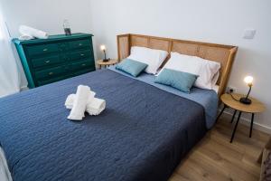 1 dormitorio con 1 cama azul y 2 toallas blancas en Forte Beach House, en Nazaré