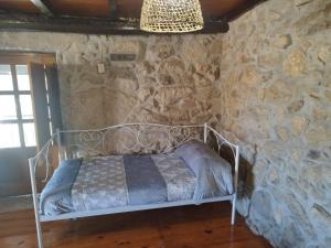 1 dormitorio con cama de metal en una pared de piedra en CASA JS, en Ourense