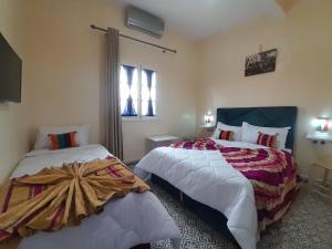 1 dormitorio con 2 camas y ventana en Hotel Mentaga en Taroudant