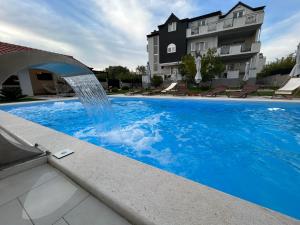 a pool with a water fountain in front of a building at Apartments Angelo in Bibinje
