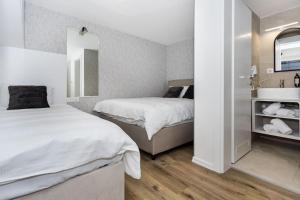 萨拉热窝Royal Grey Apartment的一间卧室，配有两张床、一个水槽和一面镜子