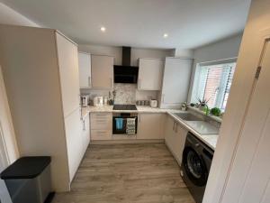 cocina con armarios blancos y lavavajillas en Enjoyable Home, en Sunderland