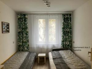 1 dormitorio con 2 camas y ventana en Apartamenty Asia Kraków, en Cracovia
