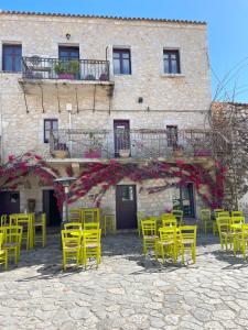 a group of yellow tables and chairs in front of a building at kir-Yiannis stonehouse @Areopoli in Areopoli