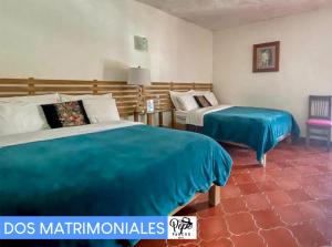 a bedroom with two beds with blue sheets and a chair at Hotel Pepe Pancho in San Cristóbal de Las Casas